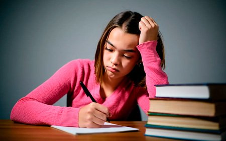 Девочка сидит за столом с книжками