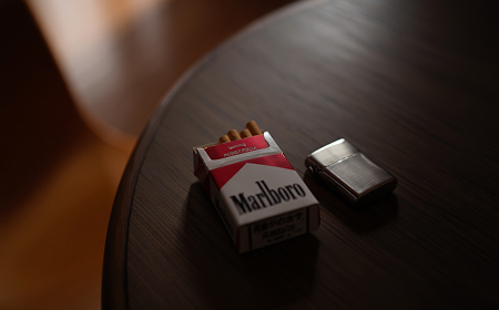 Две пачки сигарет и рассыпанные сигареты на деревянном столе